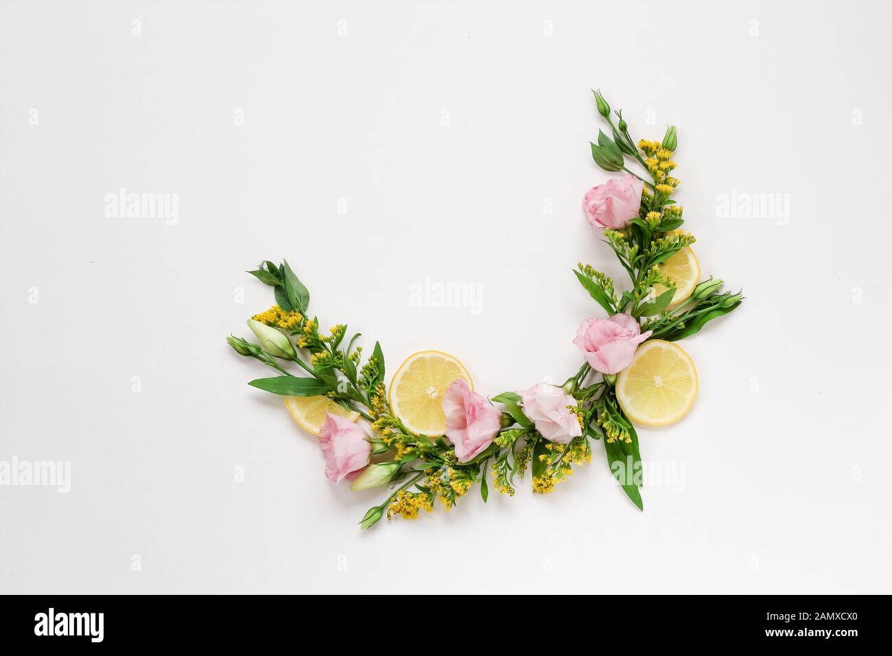 Creative arrangement of pink and yellow flowers with lemons on a white background with a copy space Stock Photo
