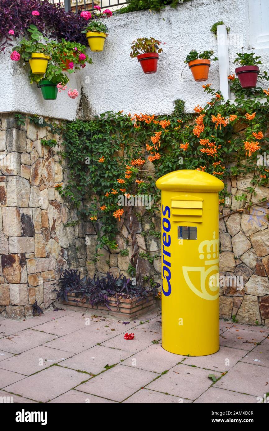 Yellow Correous mail box Spanish post box in corner of a flowery town