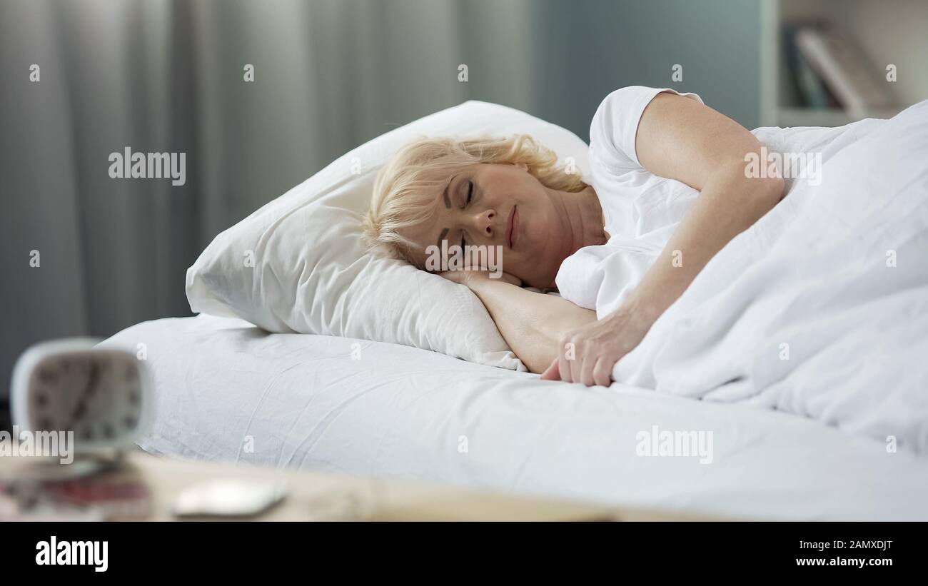 Attractive mature female sleeping in bed, rest at home, healthy lifestyle, relax Stock Photo