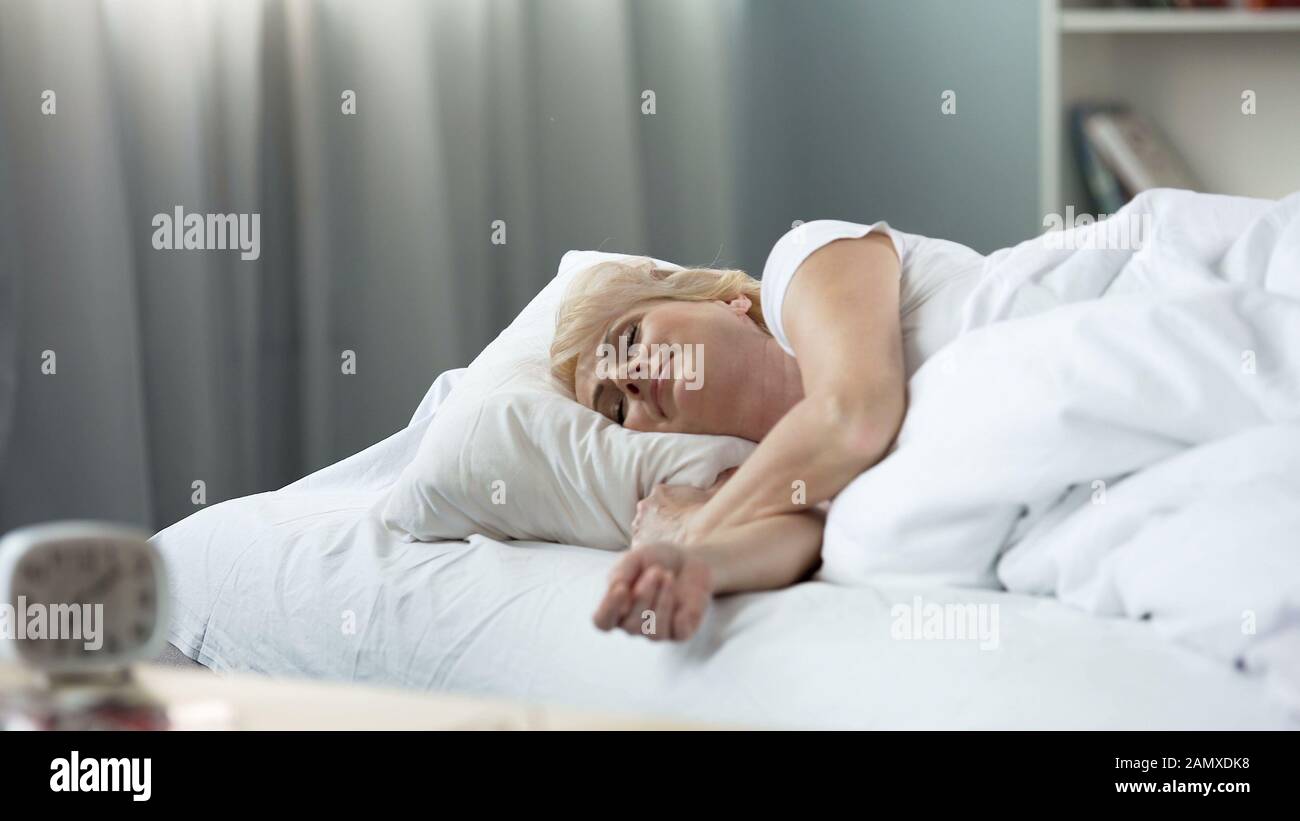 Blond senior woman sleeping in bed orthopedic mattress, healthy rest, relaxation Stock Photo