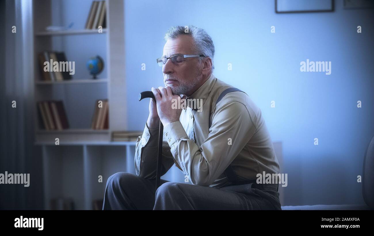 Lonely old man leaning on walking stick, dreaming, remembering youth, nostalgia Stock Photo