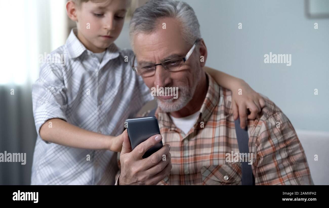 Boy teaching grandpa to use smartphone, digital nation against older
