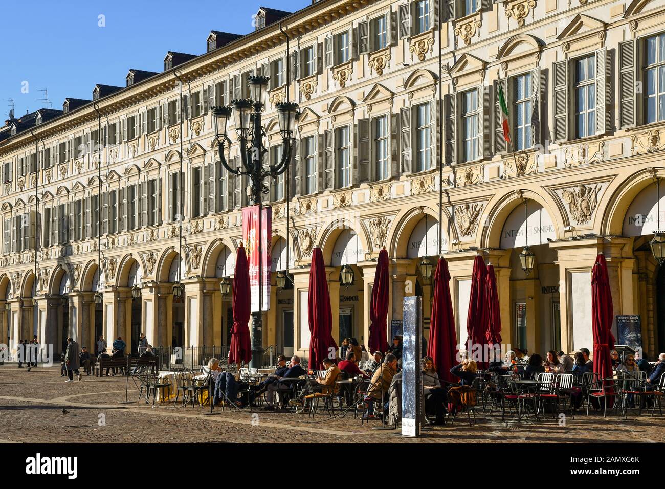 Glimpse of Piazza San Carlo square in the centre of Turin with people enjoying the sun in a sidewalk café on Christmas day, Piedmont, Italy Stock Photo