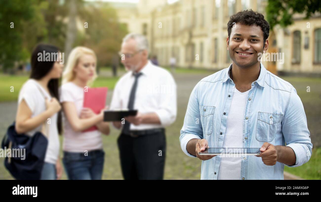 Cheerful mixed-race male holding tablet, using mobile application for education Stock Photo
