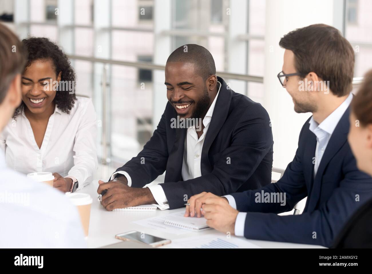 Smiling diverse employees laugh brainstorming at office meeting Stock ...