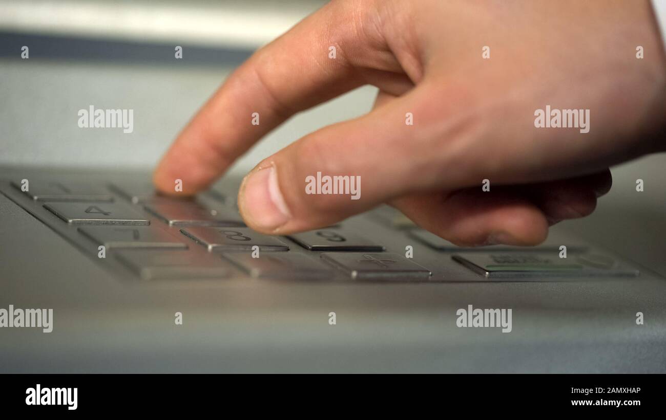 Male hand using ATM, inserting unique personal code and pressing buttons Stock Photo
