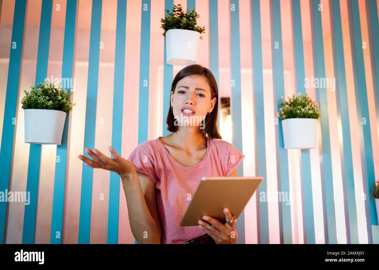 Confused shocked beautiful young woman looking at tablet computer Stock Photo