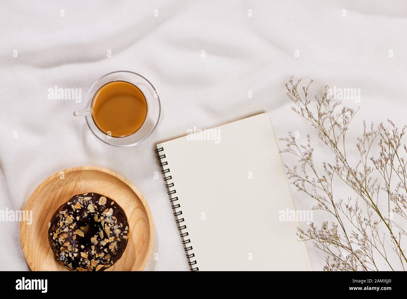 Top view flat lay of tea mug, flowers, notebook and donut cake. Text space Stock Photo