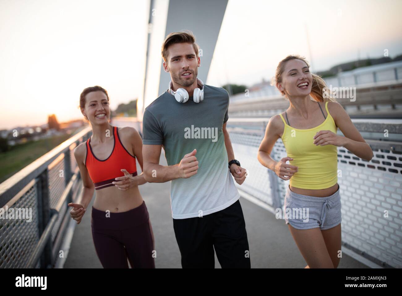 Athletic fit people exercising and running together outdoors Stock