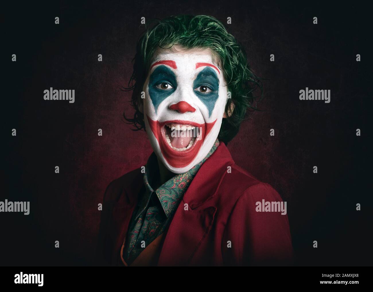smiling boy dressed as Joker on dark background Stock Photo