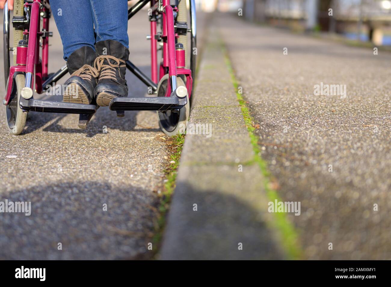 Low angle view along the curb of a wheelchair with disabled person in a