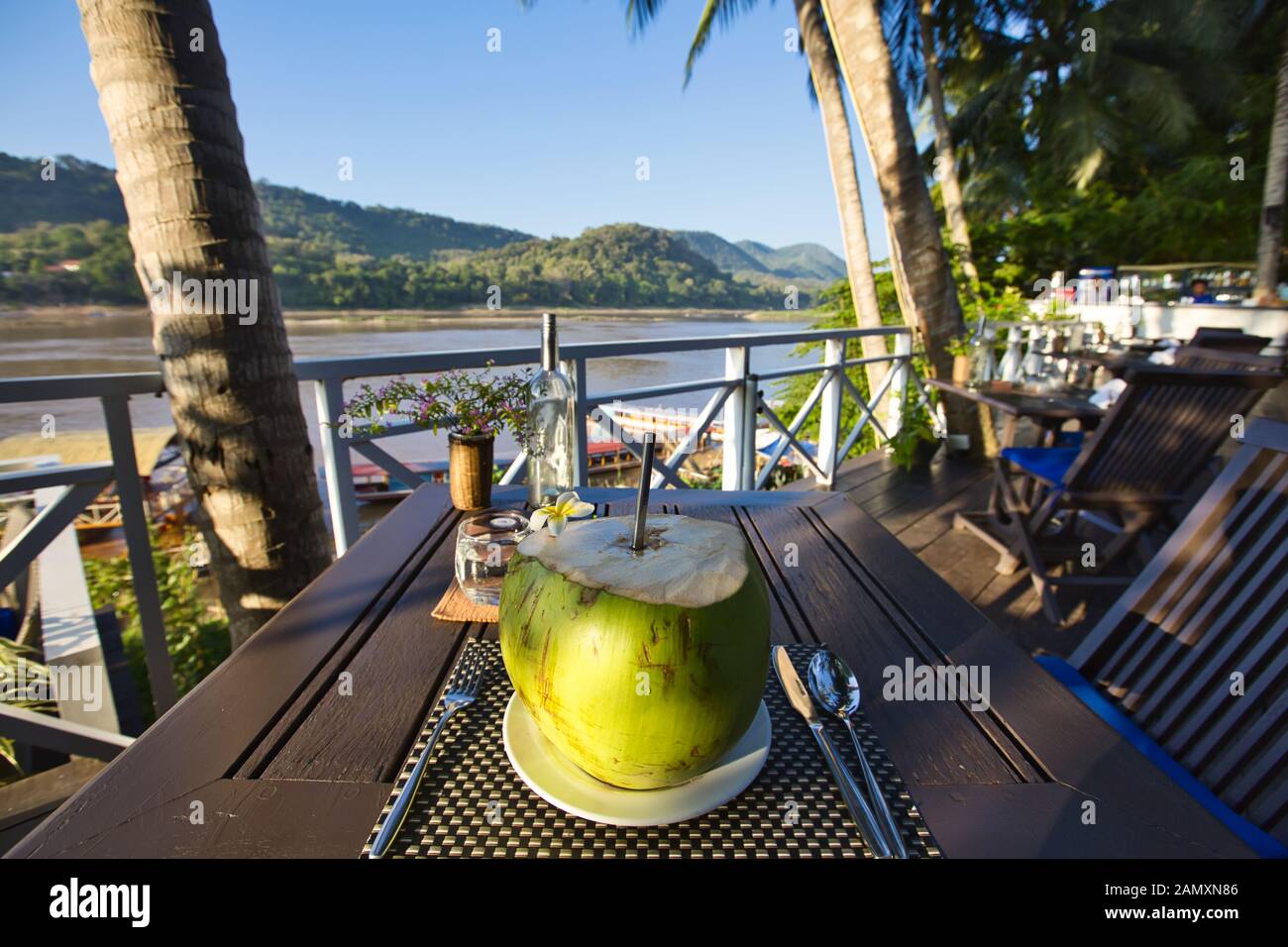 Coconut drink at an outdoor restaurant by the Mekong River in Luang Prabang, Laos Stock Photo