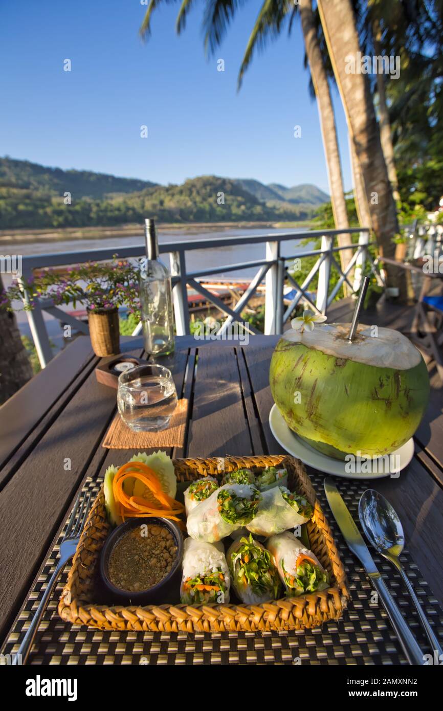 Coconut drink at an outdoor restaurant by the Mekong River in Luang Prabang, Laos Stock Photo
