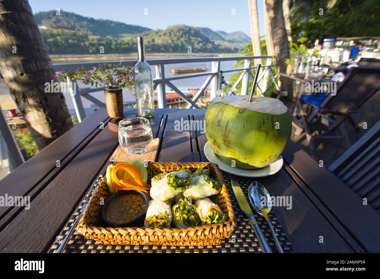 Coconut drink at an outdoor restaurant by the Mekong River in Luang Prabang, Laos Stock Photo