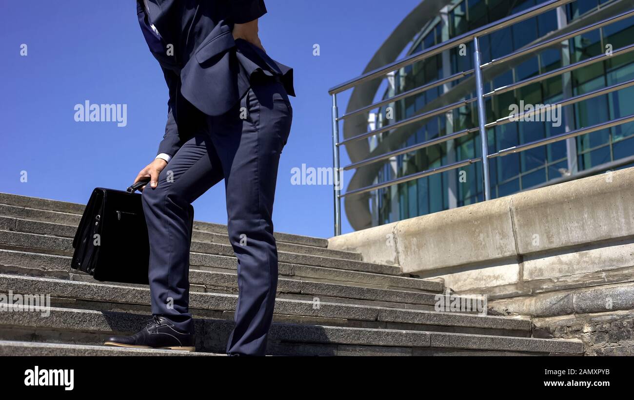 Business worker in 40s feeling sharp back pain, standing up, sedentary