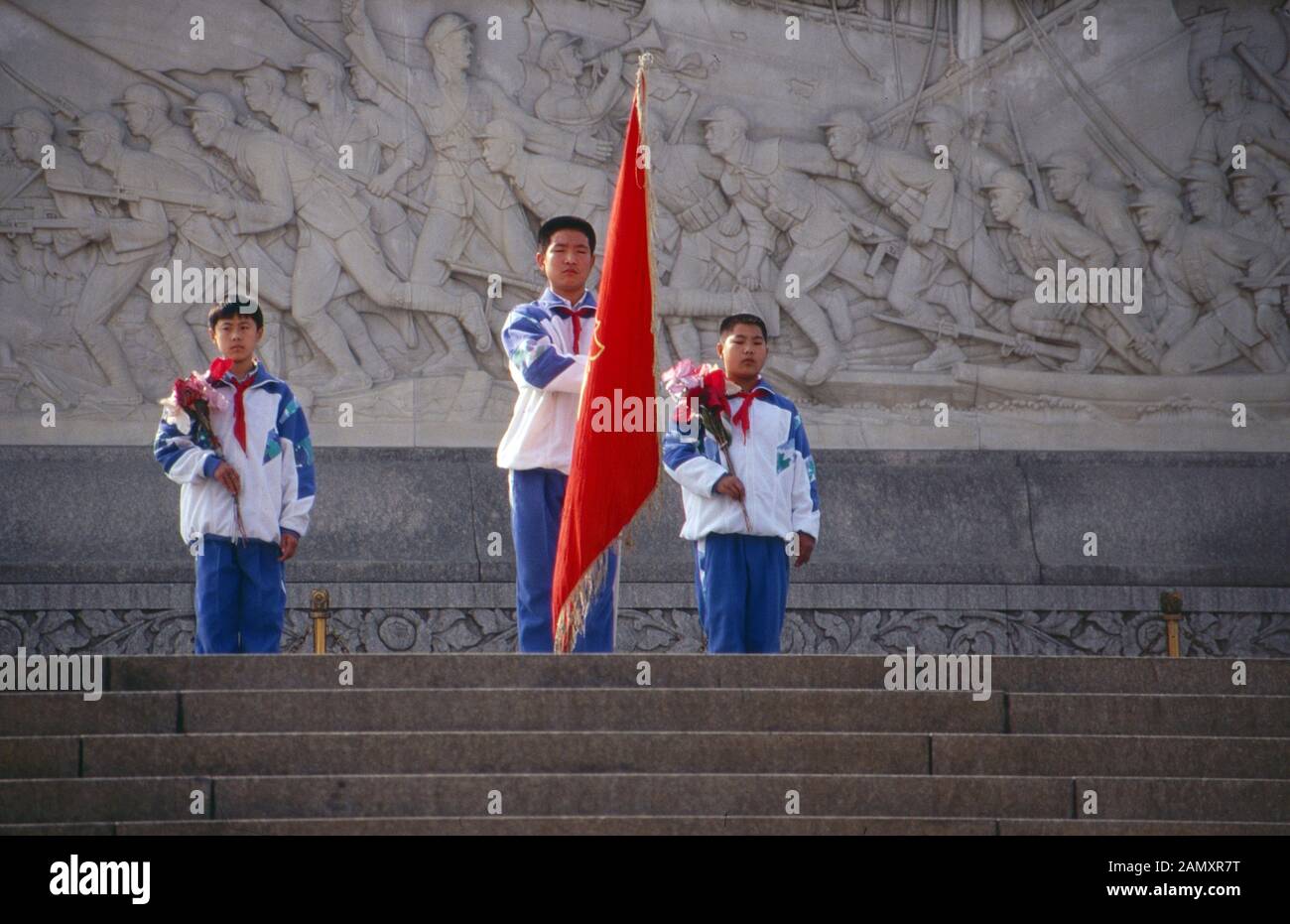 Drei junge Pioniere mit der Staatsflagge auf dem Platz des Himmlischen Friedens in Peking, China um 1990. Three boy scout pioneers with the flag on Tiananmen Square at Beijing, China around 1990. Stock Photo