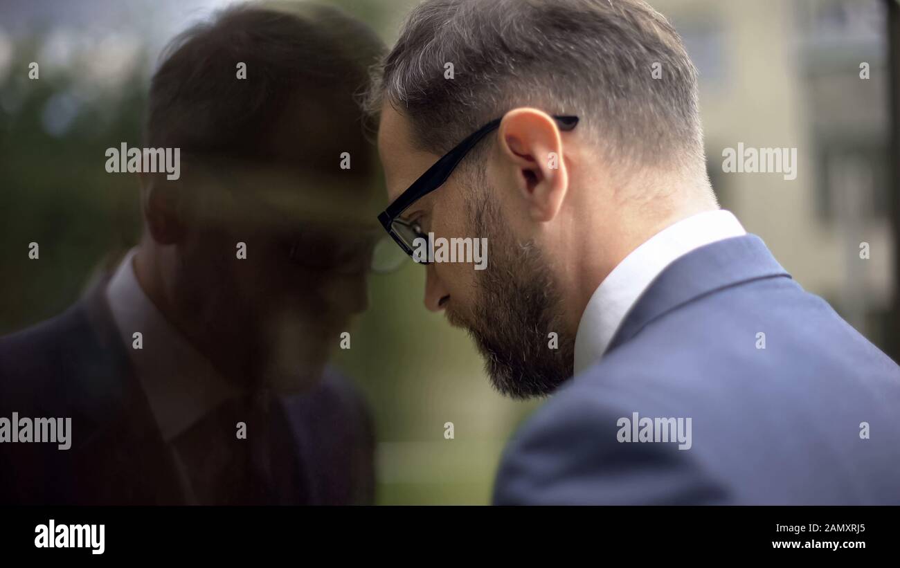 Thinking manager leaning on office wall, work failure problem, frustration Stock Photo