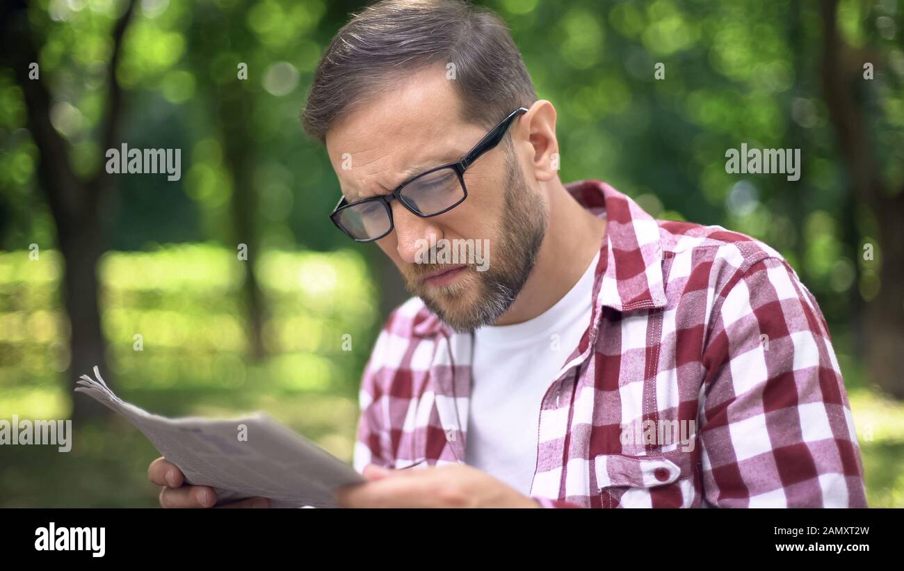 Man with poor sight trying to read newspaper in park, farsightedness, myopia Stock Photo