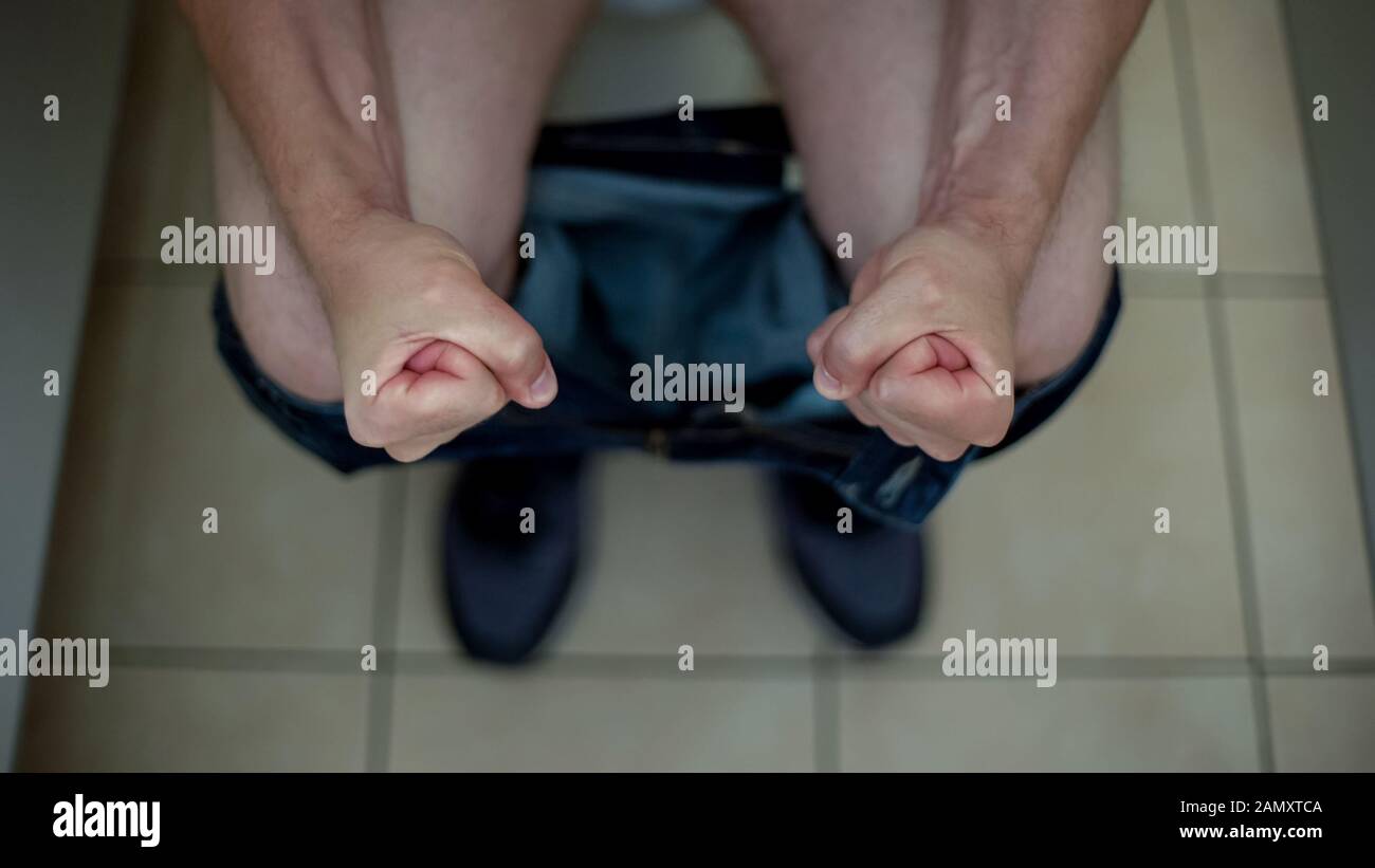 Man sitting toilet suffering from constipation, hemorrhoid problem