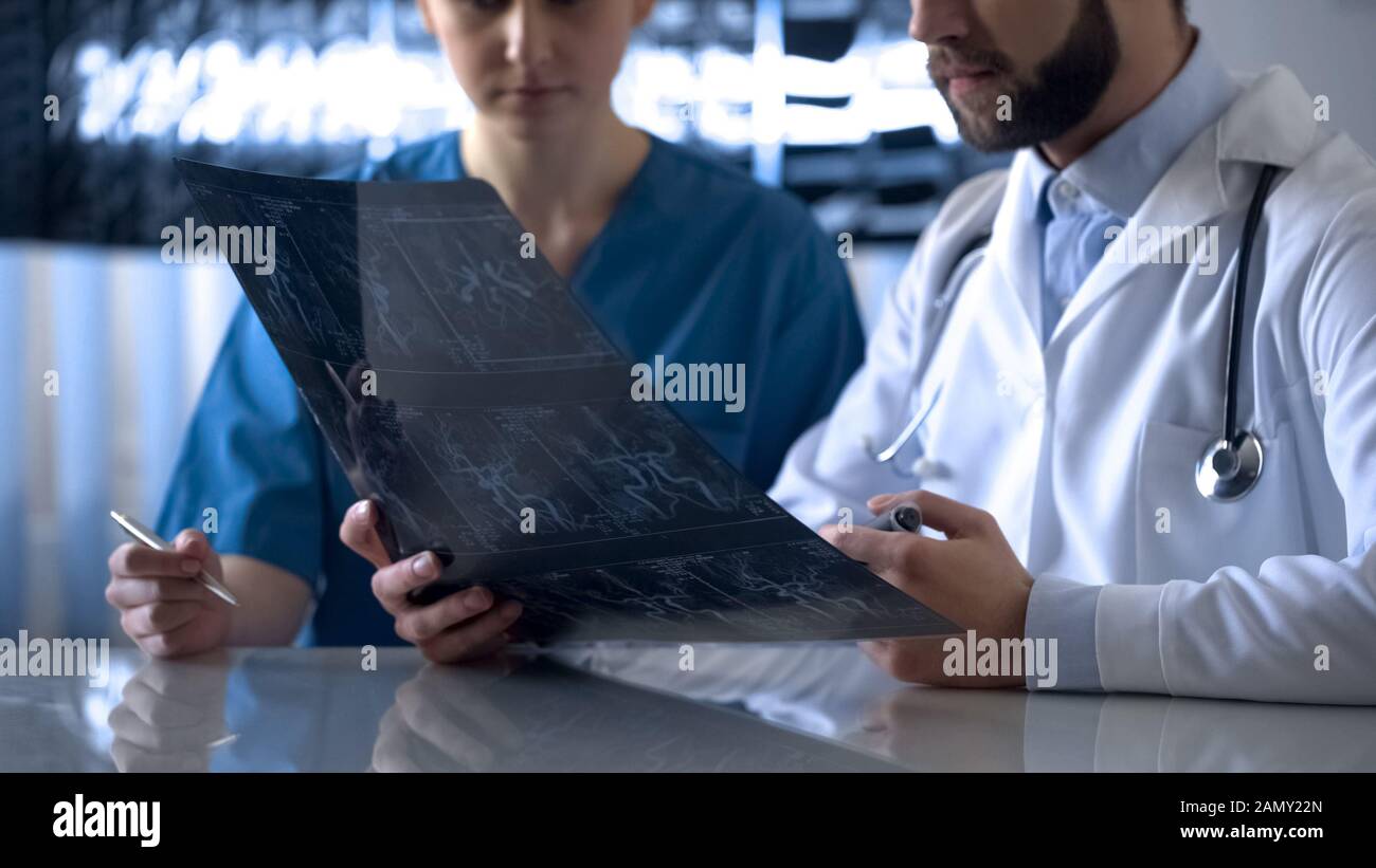 Neurosurgeon and anesthetist discussing cerebral vessels x-ray before operation Stock Photo