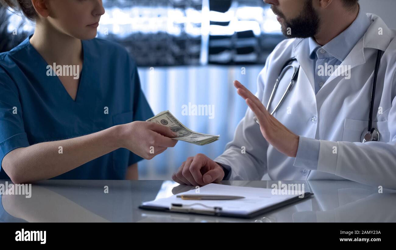 Male doctor refusing bribe from young female intern, corruption in medicine Stock Photo
