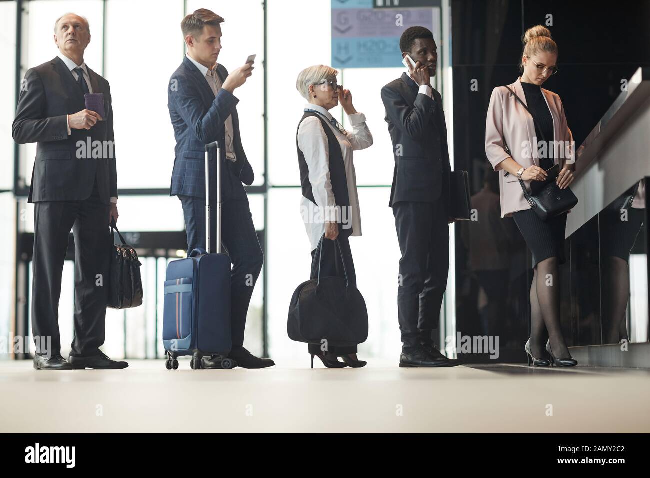 Group of business people with luggages standing in a queue and registering on the reception at the airport Stock Photo