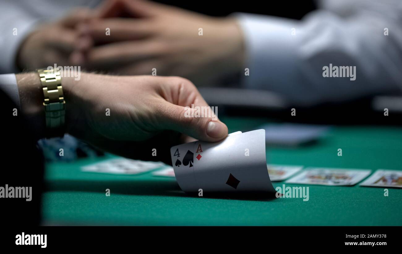 Unfortunate poker game, hand of casino player checking bad card combination Stock Photo