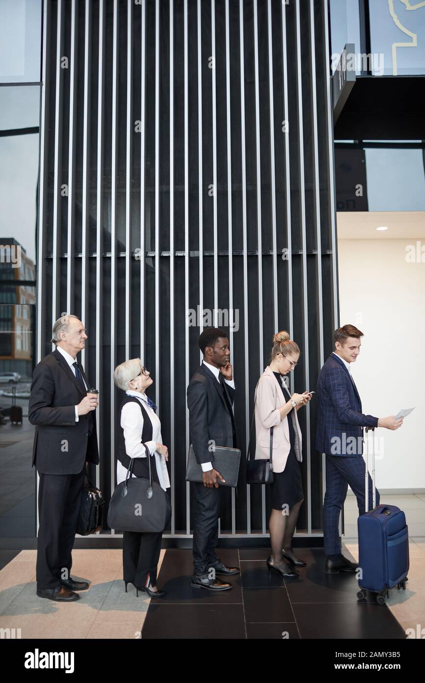 Group of business people with luggage standing in the queue and waiting for their registration at the airport Stock Photo
