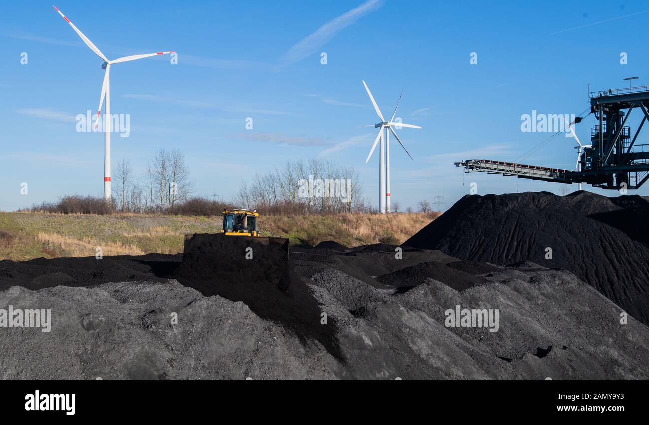 Hohenhameln, Germany. 15th Jan, 2020. Hard coal is stored in the coal port of the Mehrum coal-fired power plant in the district of Peine. There is a wind turbine in the immediate vicinity. In the evening, a top-level meeting on the coal exit takes place in the Chancellery. This involves a precise timetable for ending climate-damaging coal-based electricity generation. Germany wants to gradually phase out the climate-damaging combustion of coal for electricity generation by 2038. Credit: Julian Stratenschulte/dpa/Alamy Live News Stock Photo