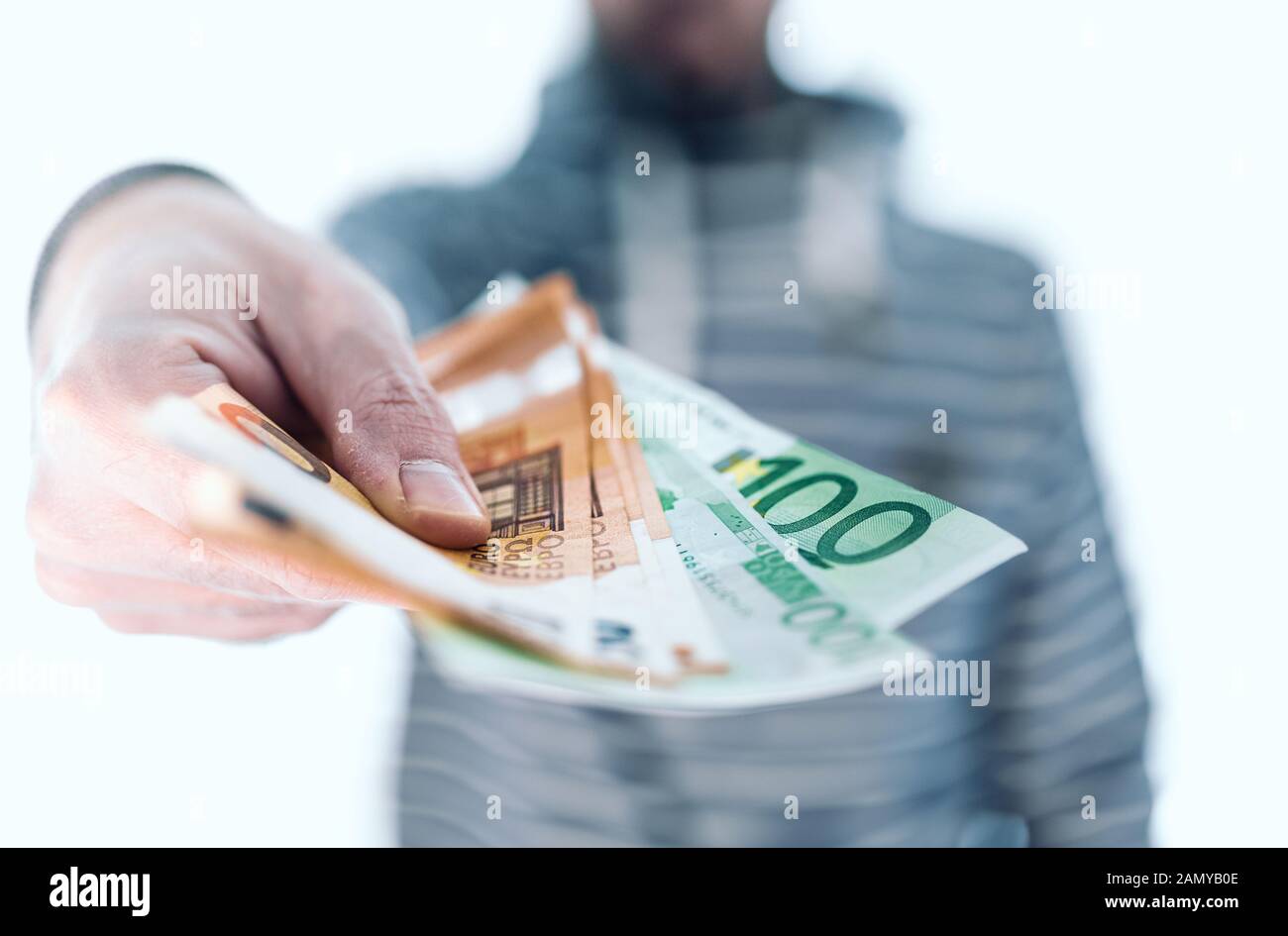 midsection of man holding banknotes in his hand handing it over to someone, paying with cash concept Stock Photo