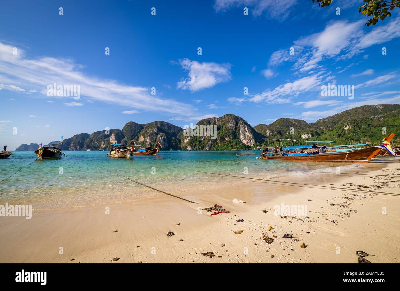 traditional wooden longtail boats parked at a beach in Phi Phi Island. Clear water and clean beach. Stock Photo