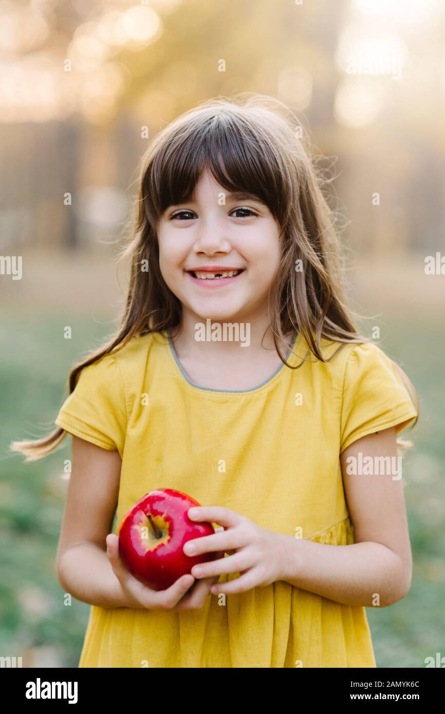 Child picking apples on farm in autumn orchard. Loss of milk tooth