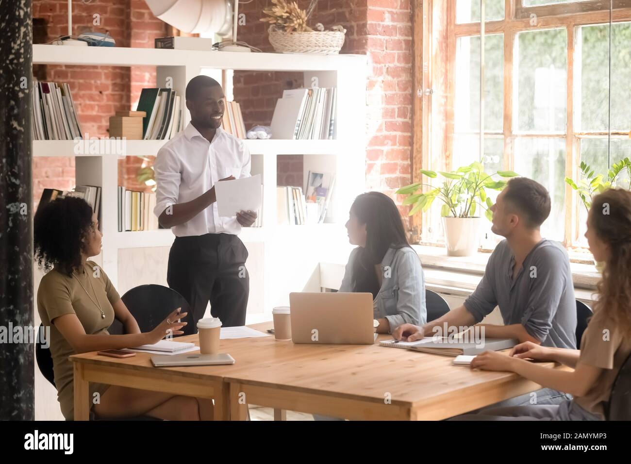 Black millennial man stand talking collaborating with diverse group Stock Photo