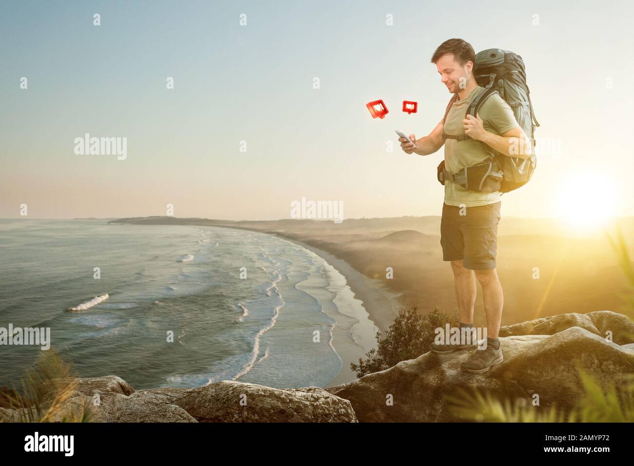 Hiker in front of a beautiful coastline is using a smartphone Stock Photo