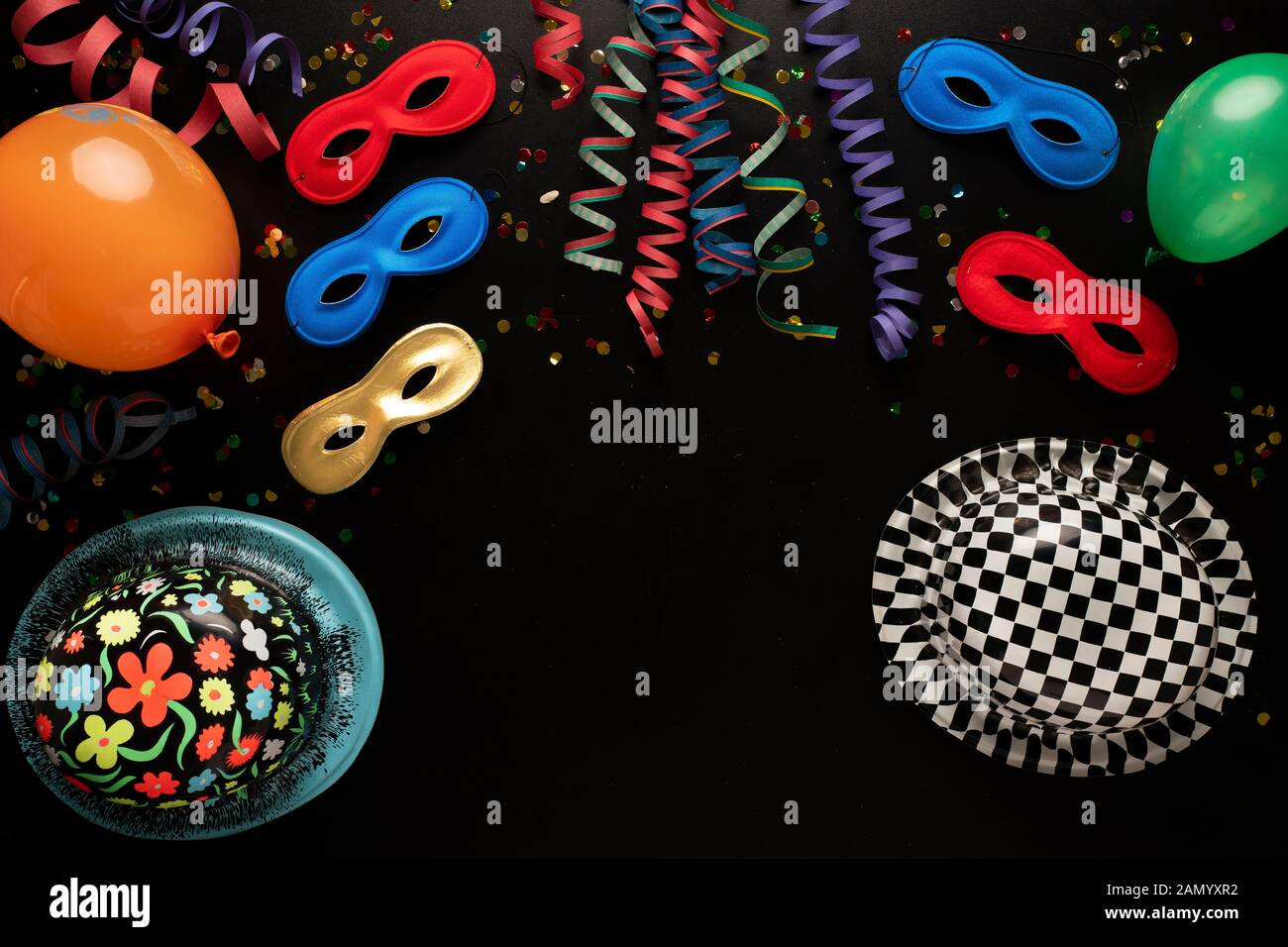 Carnival objects on a black background. Coiled streamers, masks, paper skeleton, confetti, paper balloons and many other carnival objects Stock Photo