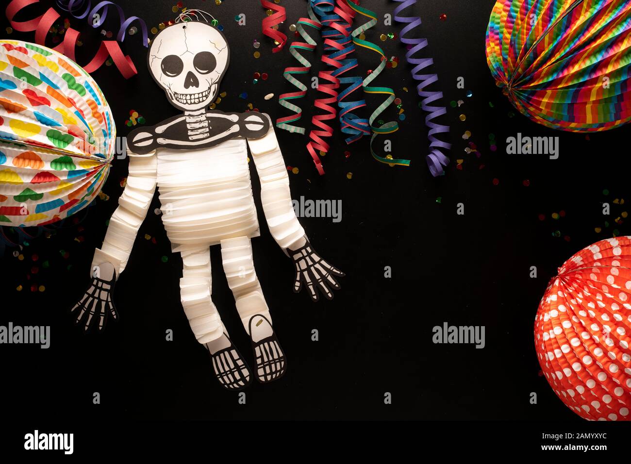 Carnival objects on a black background. Coiled streamers, paper skeleton, confetti, paper balloons and many other carnival objects Stock Photo