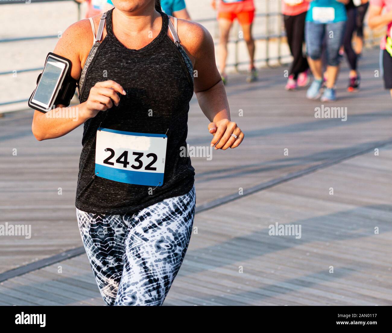 A Female Runner Is Running A 10k Race On A Boardwalk With A Phone Strapped On Her Arm And The Runners Behind Her Blurred Stock Photo Alamy