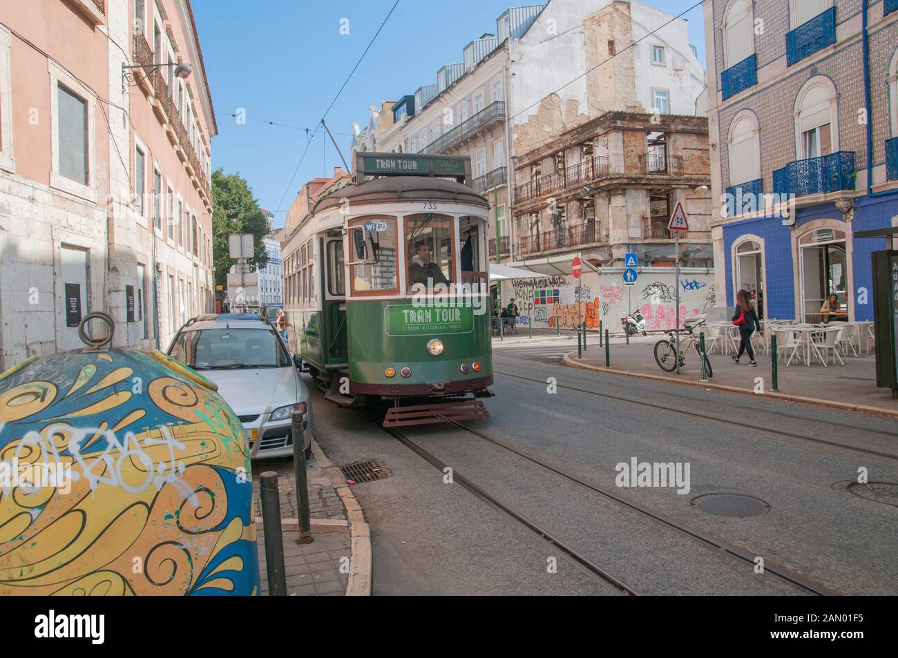 Green tram navigates the crowded narrow streets of Lisbon, Portugal Stock Photo