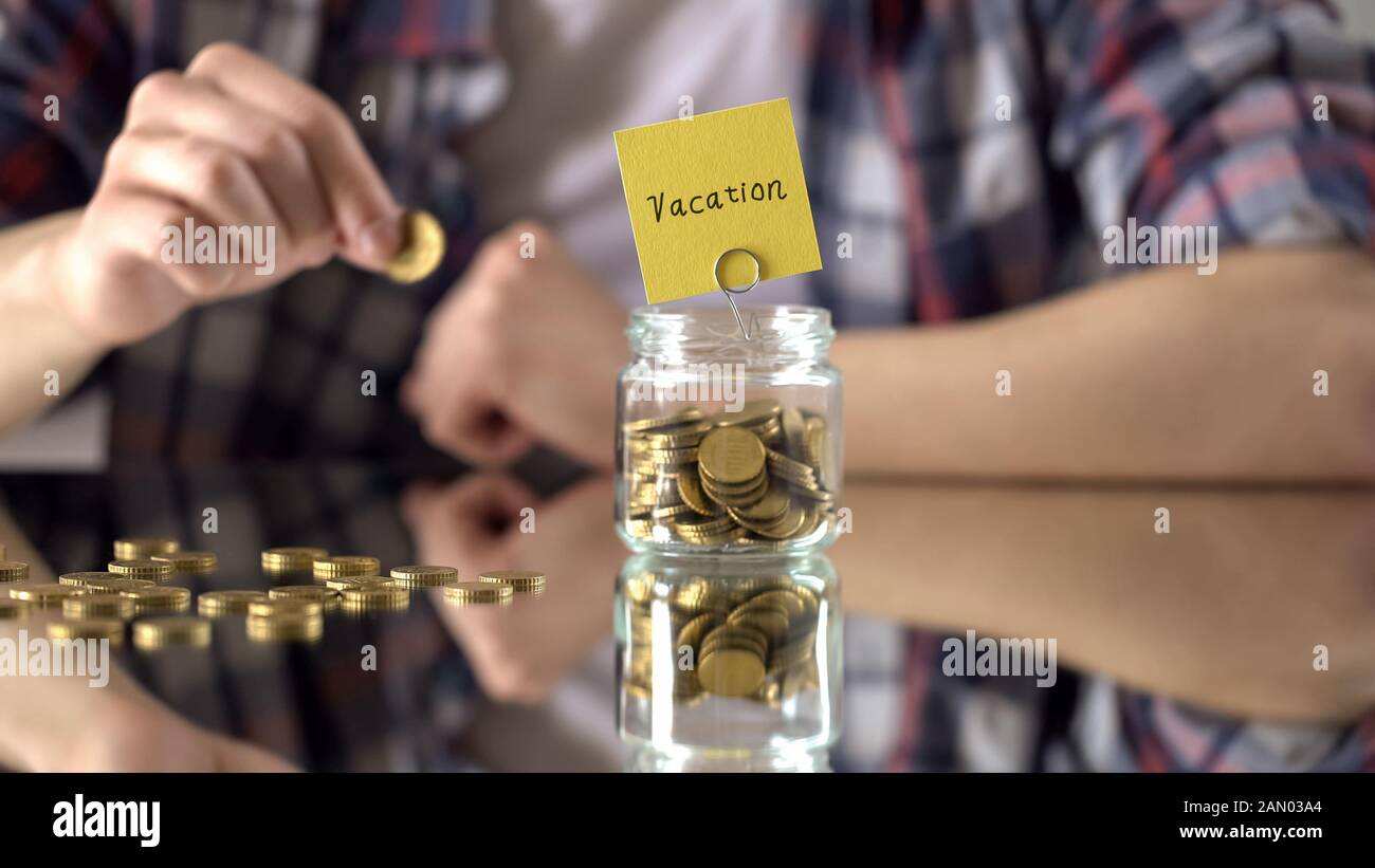 Vacation word written above glass jar with money, savings for summer holidays Stock Photo