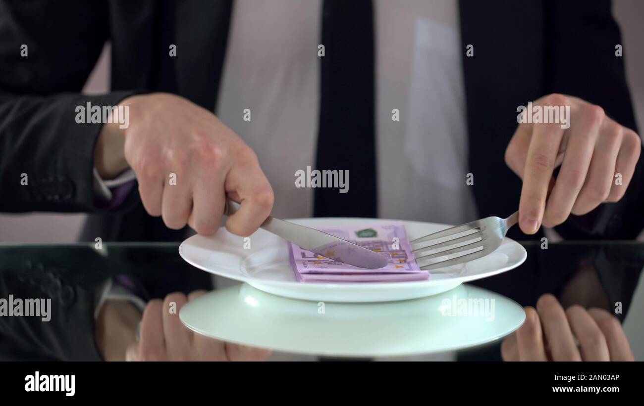 Businessman eating euro banknotes, squandering concept, embezzlement of budget Stock Photo