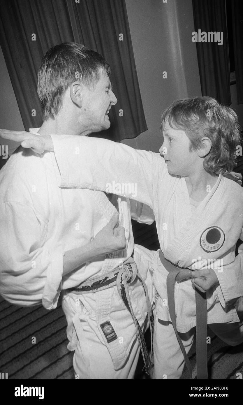 1980s, historical, a young boy practising a karate punch with an adult male instructor, England, UK. Originating from Japan and meaning 'empty hand', Karate is one of the most popular martial arts and is a striking art form, utilising elbow punches, punches and open hand techniques and kicks. A karate practitioner is called a karateka. Stock Photo
