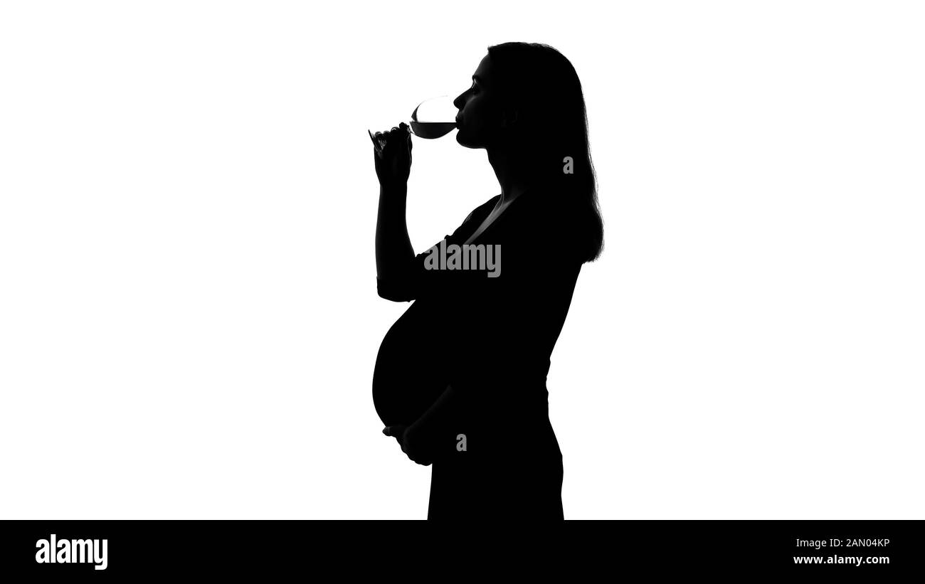 Silhouette of young pregnant woman drinking wine, unhealthy habits harm baby Stock Photo