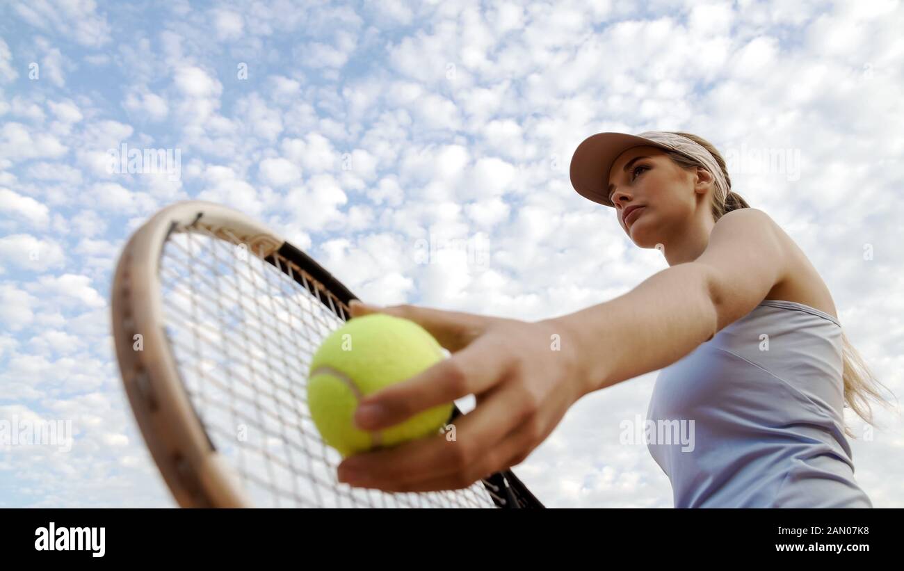 Professional female tennis player serving ball at court, motivation and sport Stock Photo