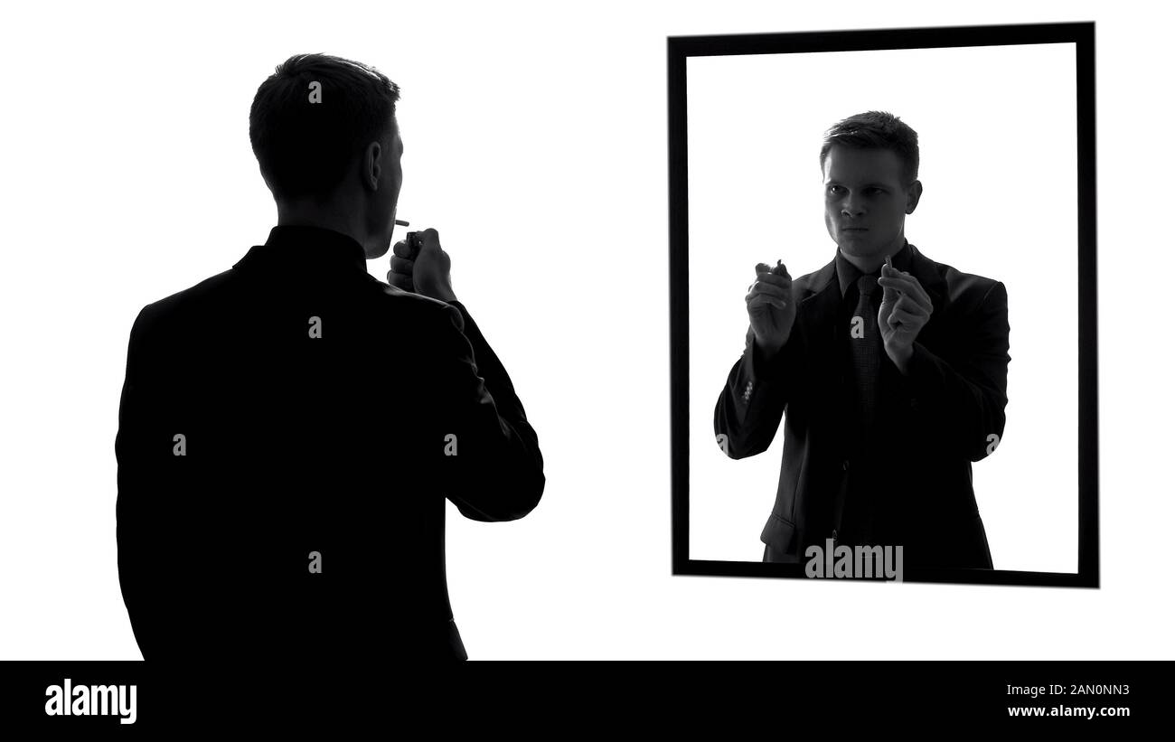 Man lighting cigarette, conscience voice asking quit smoking, mirror reflection Stock Photo