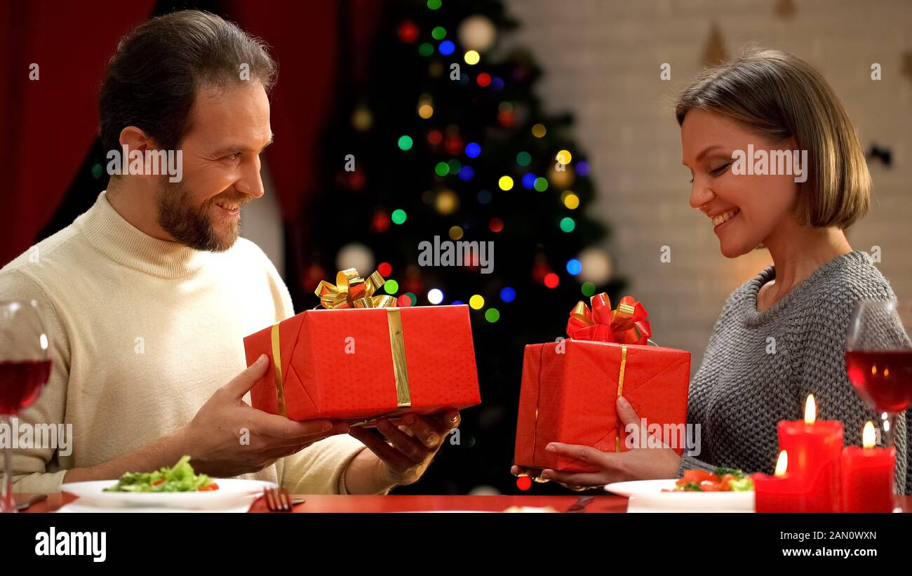 Man and lady exchanging Christmas presents, cozy romantic evening for couple Stock Photo