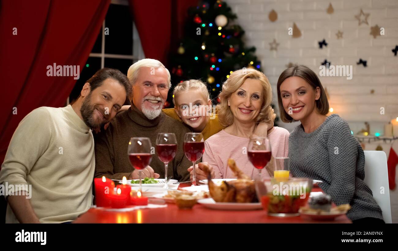 Friendly family hugging and looking into camera, Xmas dinner traditions Stock Photo