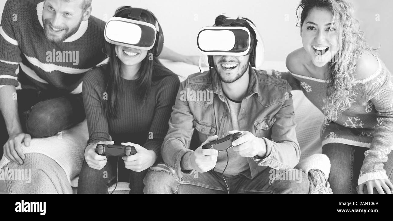 Group of millennials friends playing video games with virtual reality headset - Young people having fun with new vr trend technology - Tech, generatio Stock Photo