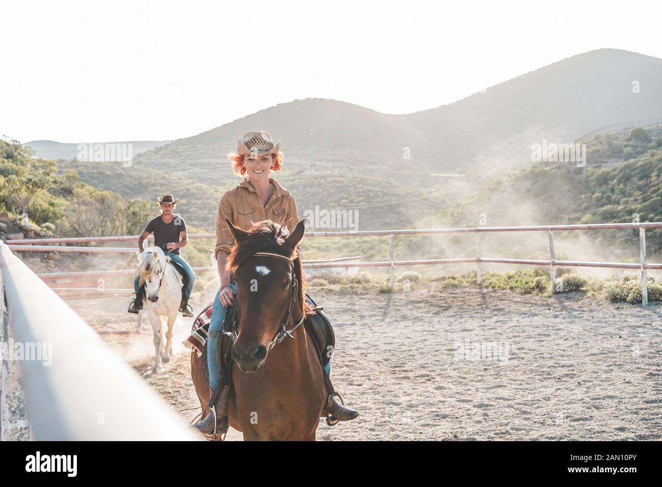 Young people riding horses inside corral Wild couple having fun in