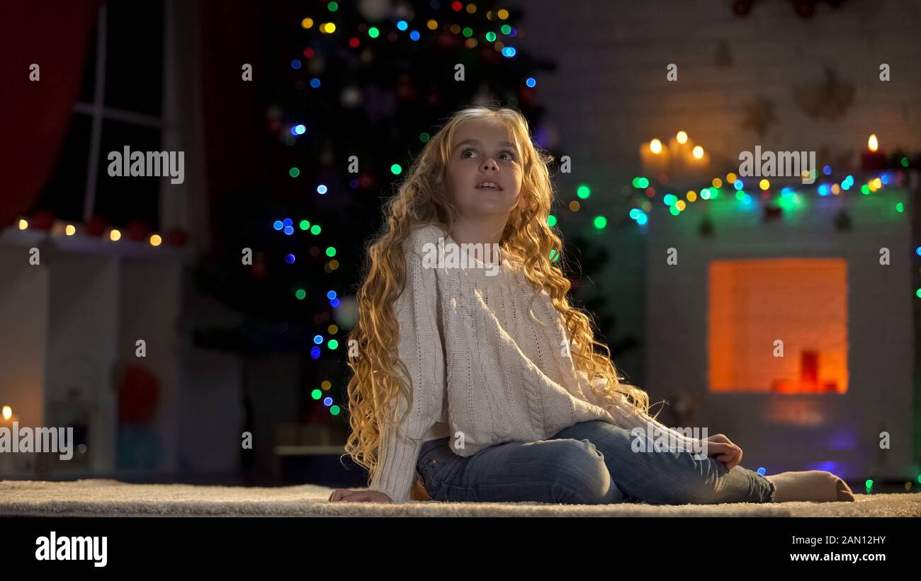 Little girl sitting on floor, waiting Santa on Christmas eve, magical moment Stock Photo