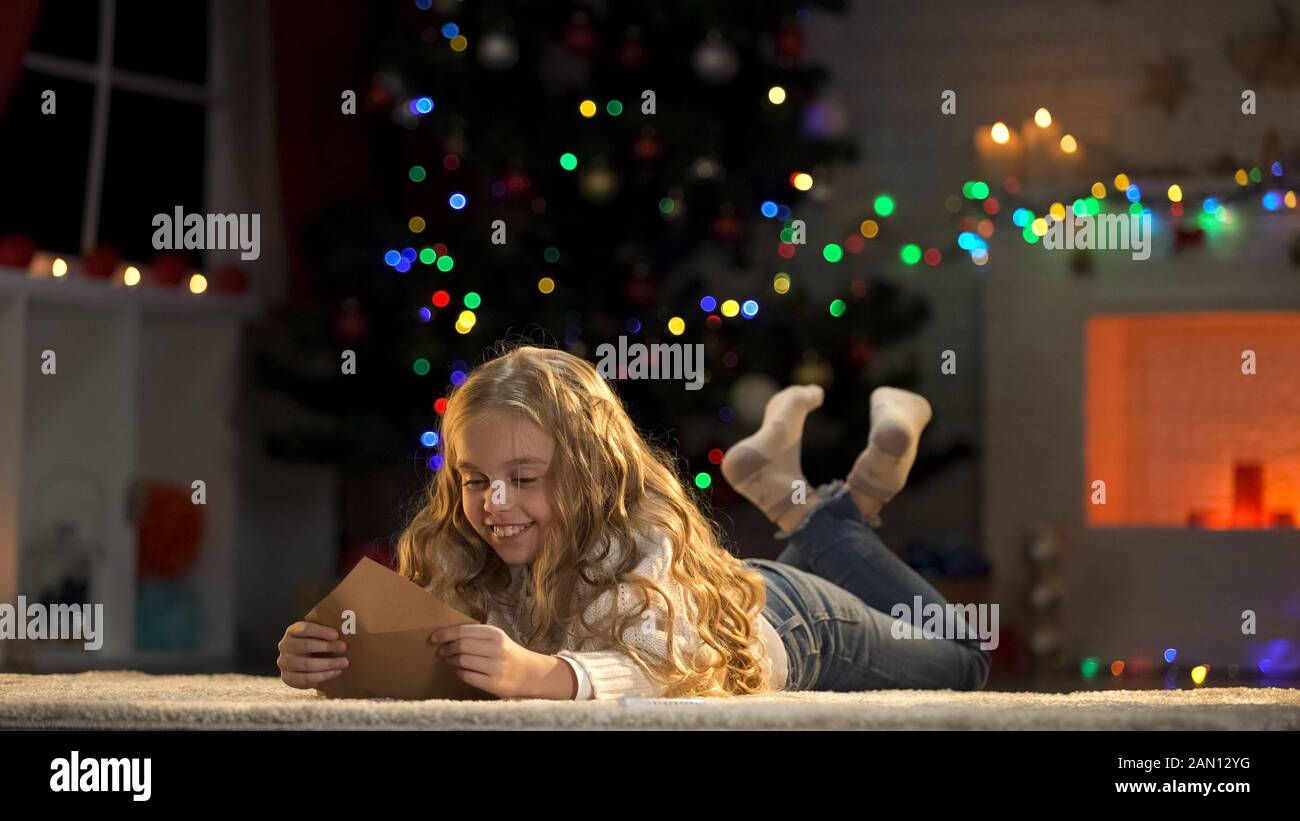 Girl opening letter from friend, greeting on Christmas eve, memory of loved ones Stock Photo